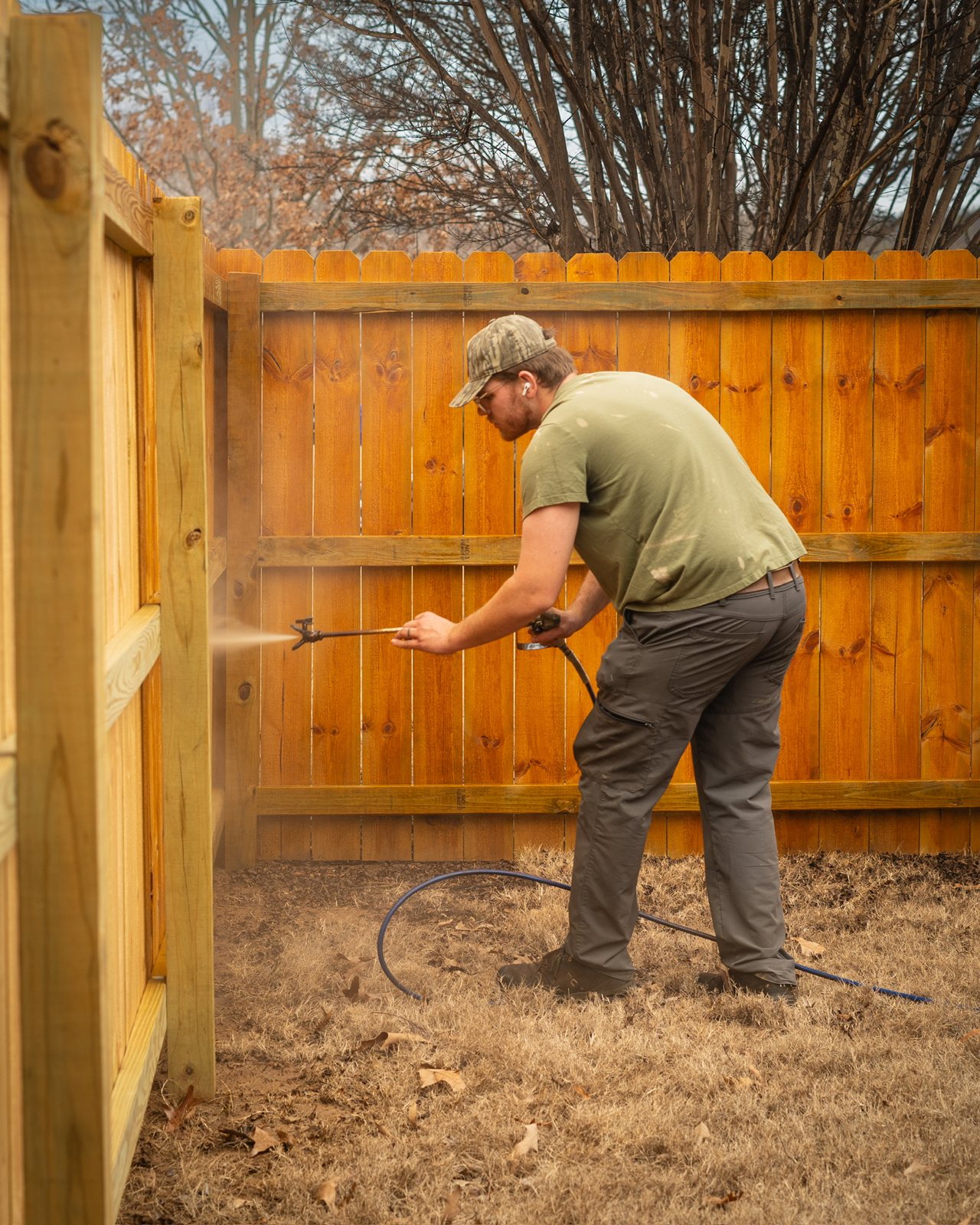 Spraying stain onto a fence